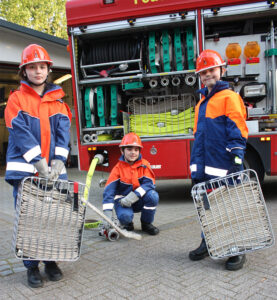 3 Kinder stehen mit der JF-spezifischen Ausrüstung vor dem LF10